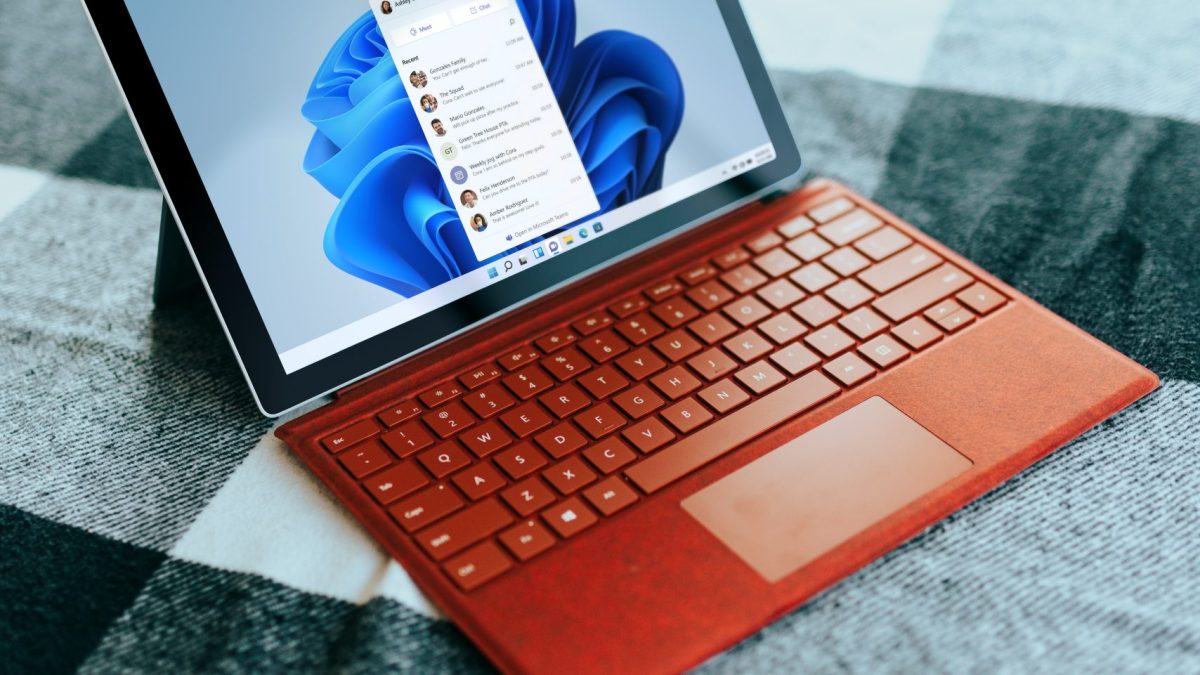 Red Surface laptop on a checkered bed by a window